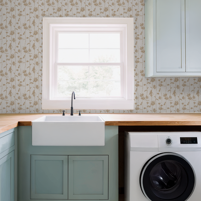 Beige floral wallpaper in a laundry room with sink and washer.