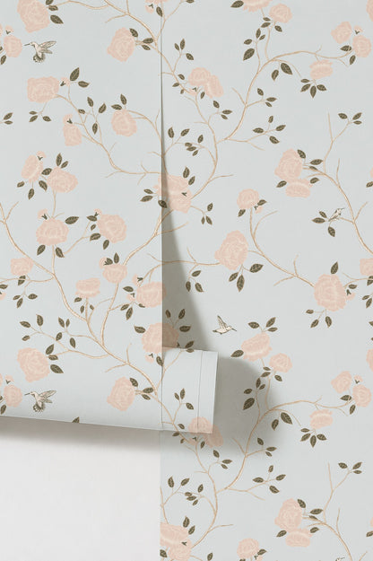 Blue wallpaper with pink roses and green vines in chinoiserie style.