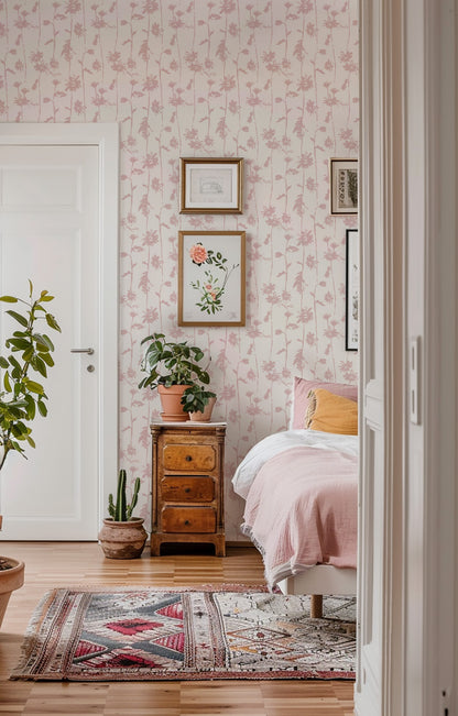 Blush pink floral wallpaper in cozy bedroom with plants and wooden furniture.