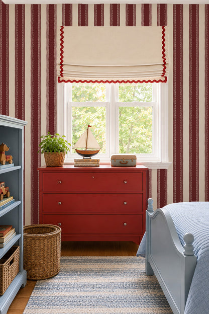 Burgundy lace stripe wallpaper in cozy bedroom with red dresser and blue bed.