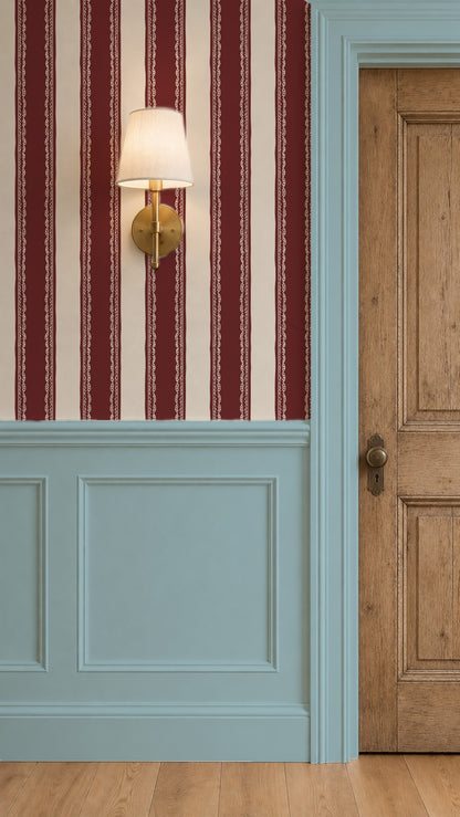 Burgundy striped wallpaper with lace detail in an elegant room with wood door and blue paneling.