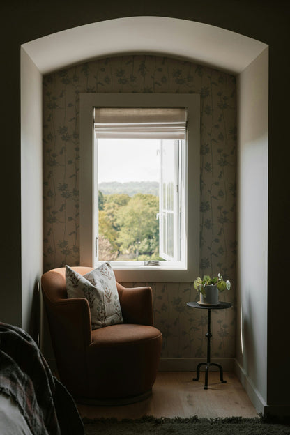 Cozy nook with floral wallpaper, armchair, and window view.