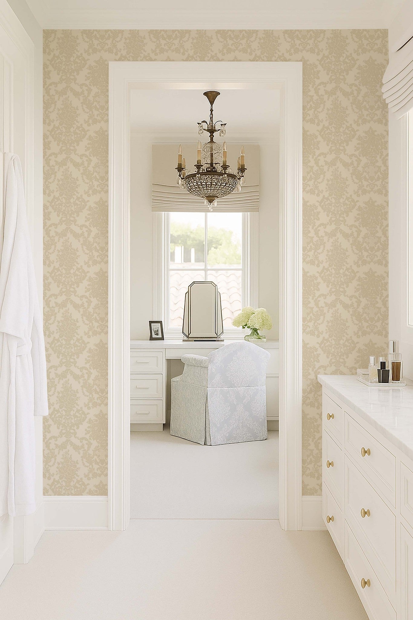 Cream damask wallpaper in elegant bathroom with chandelier and vanity.