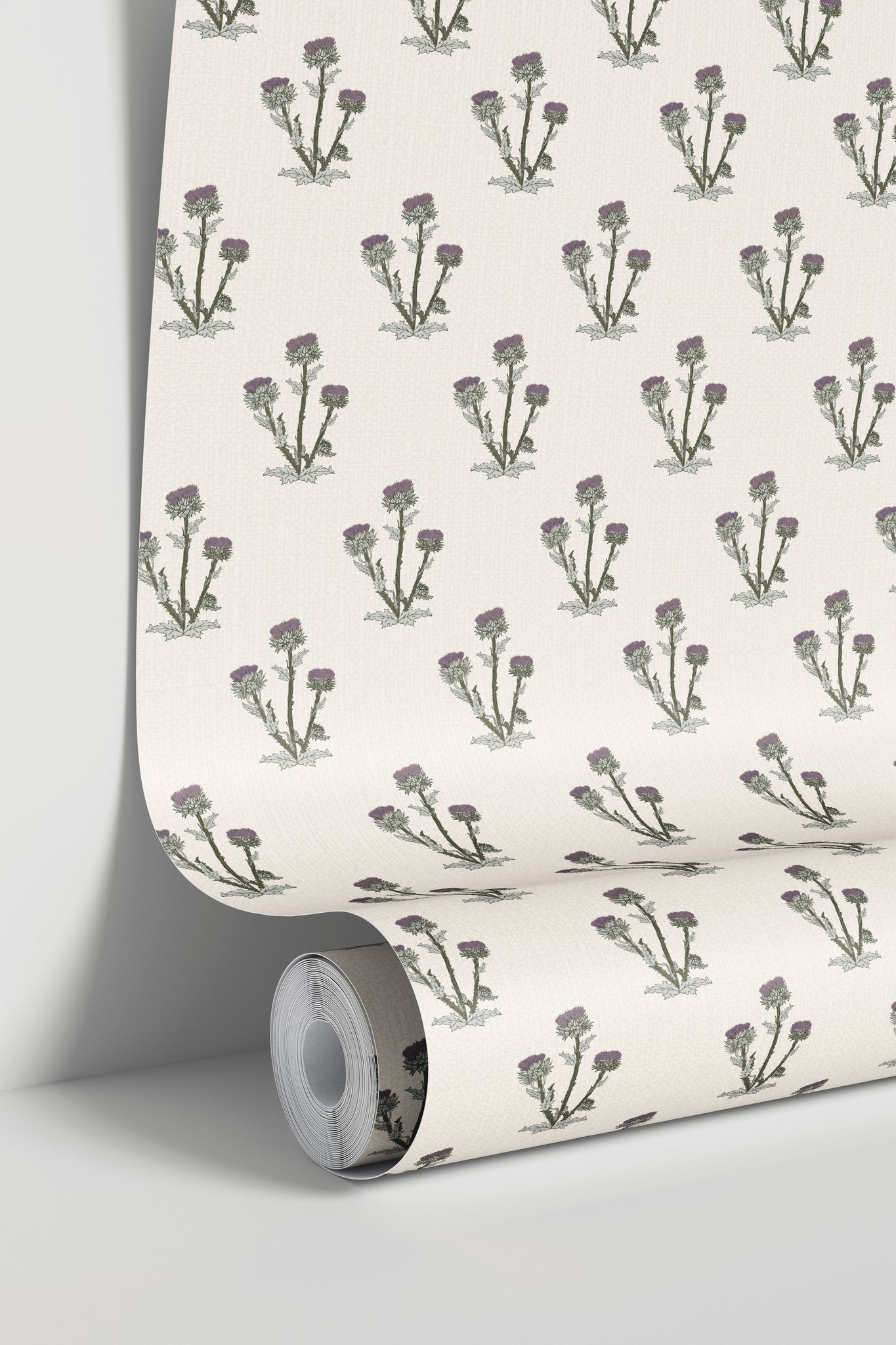 Cream wallpaper with purple and green thistle pattern in a roll.