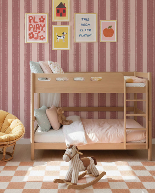 Dark pink striped wallpaper with lace detail in a vintage room with yellow chair and decor.
