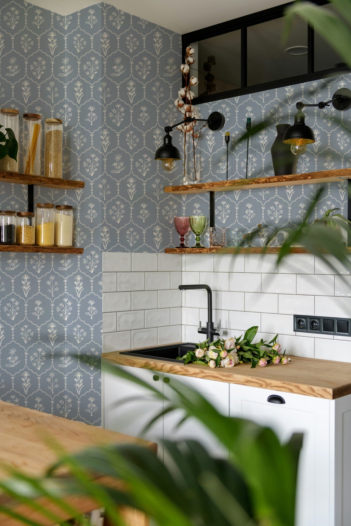 Dusty blue floral trellis wallpaper in modern kitchen with wood shelves.