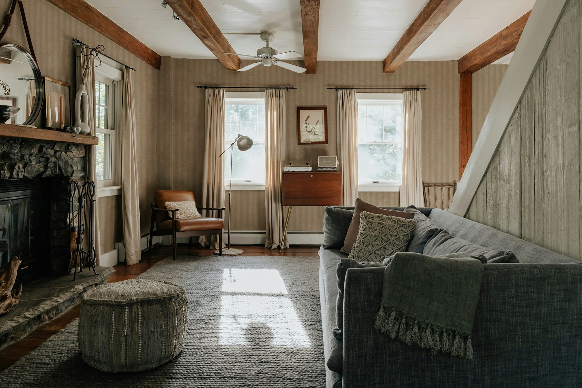 Living room with ecru striped wallpaper, gray sofa, and rustic decor.