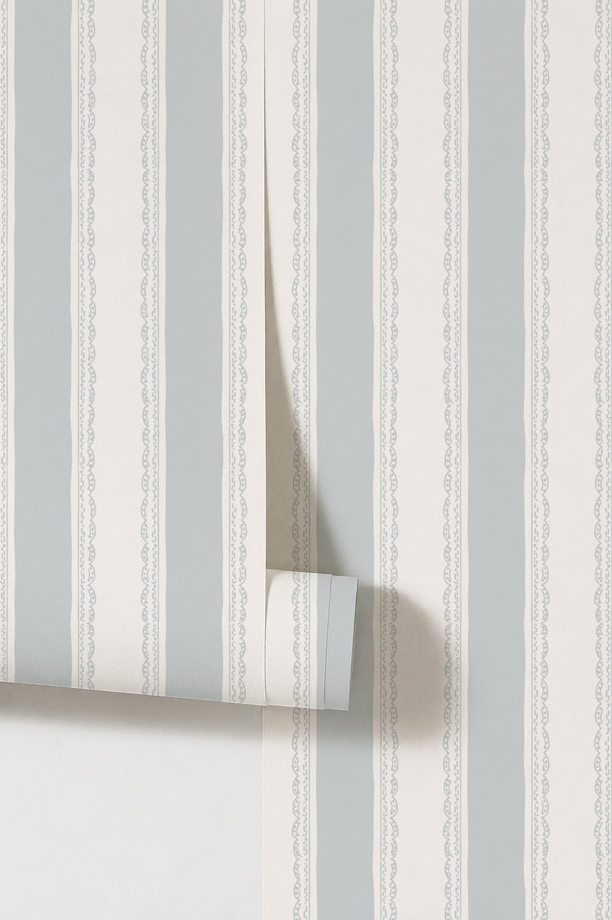 Light blue and white striped wallpaper with lace-like borders, rolled sample view.