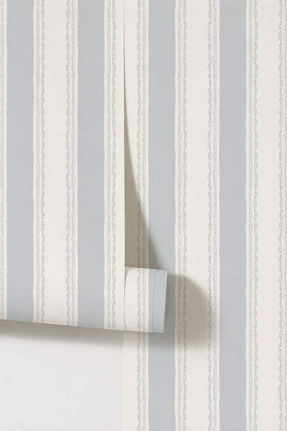 Light blue and white striped wallpaper with lace-like borders, rolled sample view.