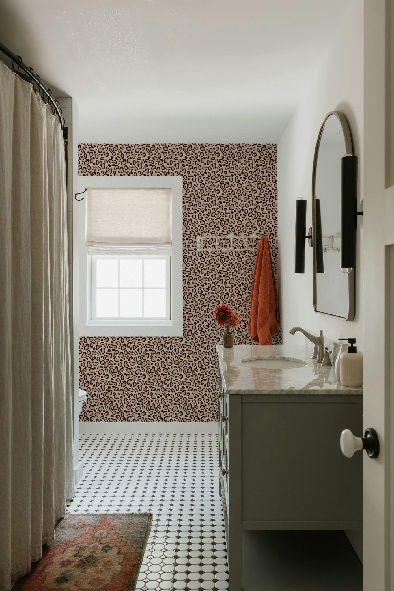 Leopard print cream wallpaper in modern bathroom with round mirror and patterned floor.