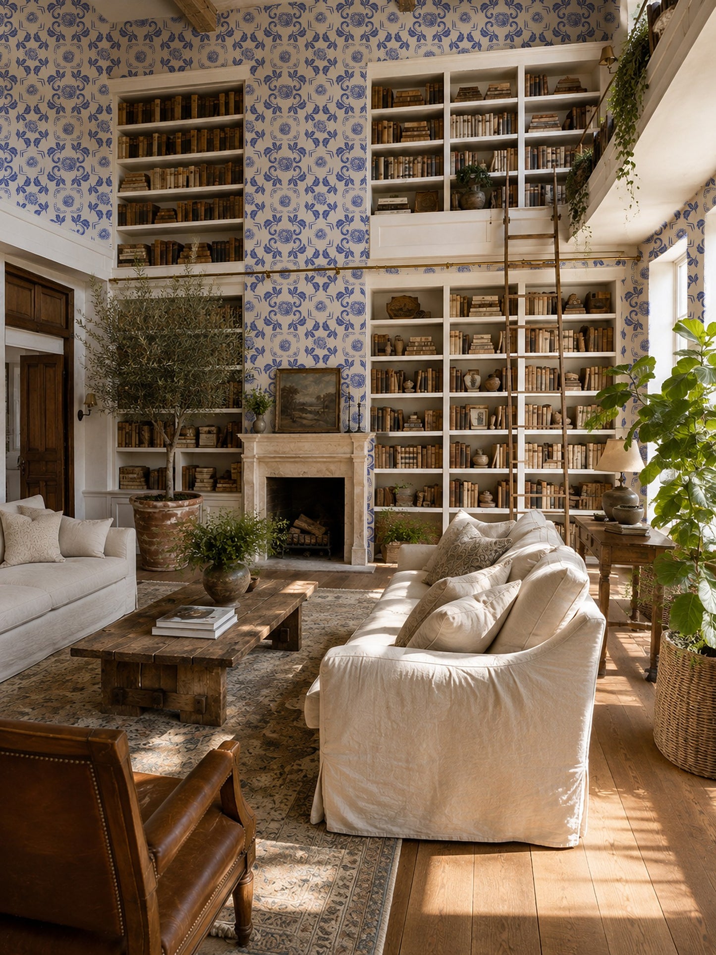 Living room with Nora Delft Blue floral wallpaper, bookshelves, and cozy seating.