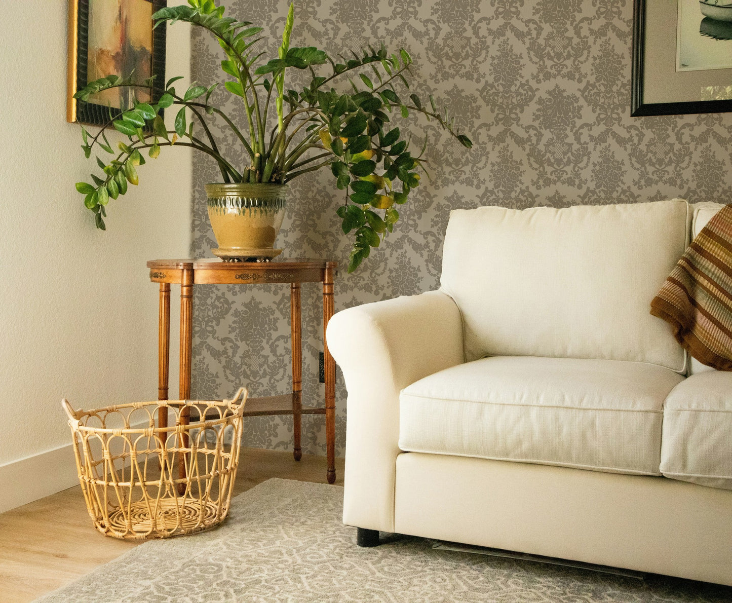 Olive green damask wallpaper in cozy living room with cream sofa and plants.