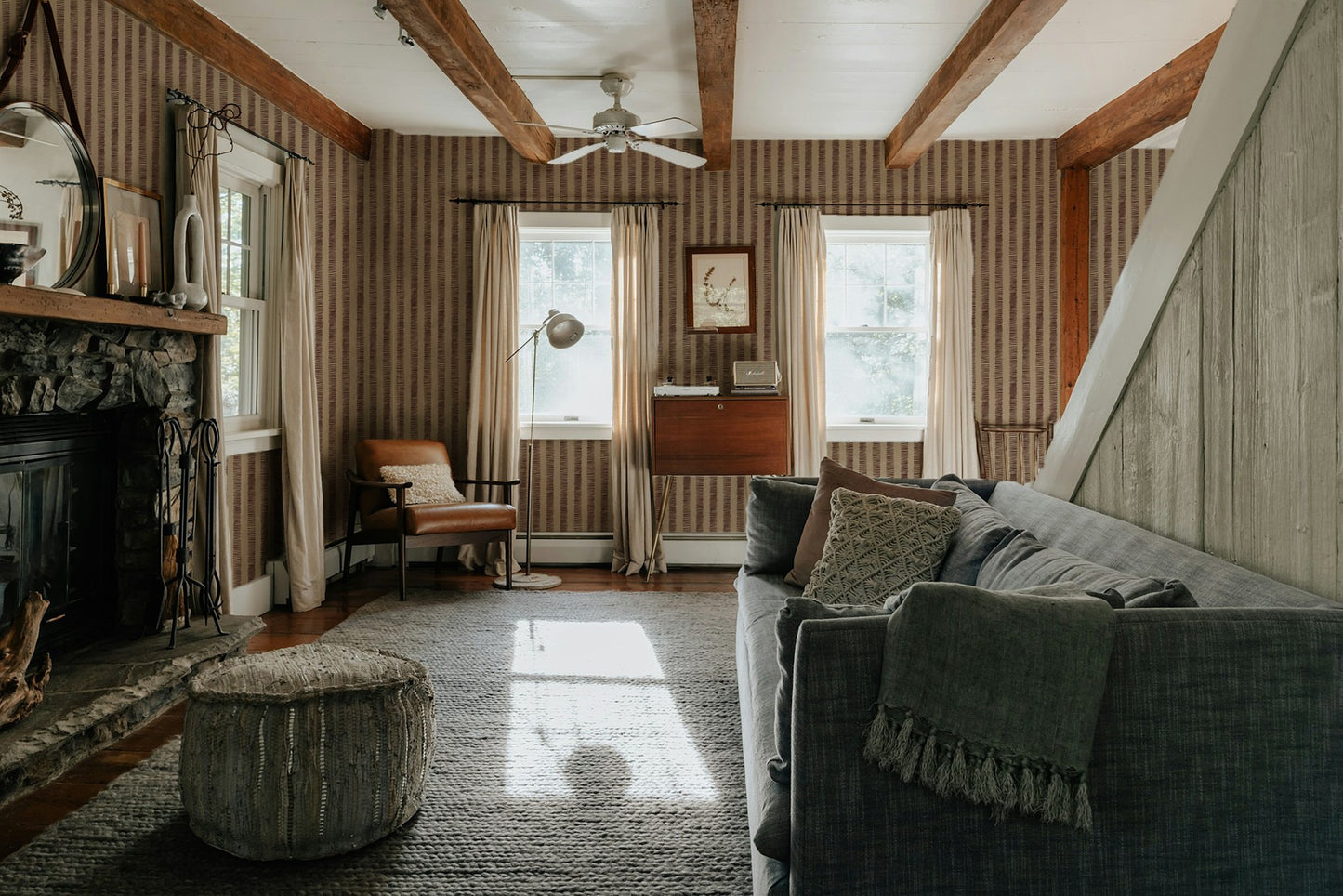 Living room with Organic Stripes Red wallpaper, rustic decor, and wooden beams.