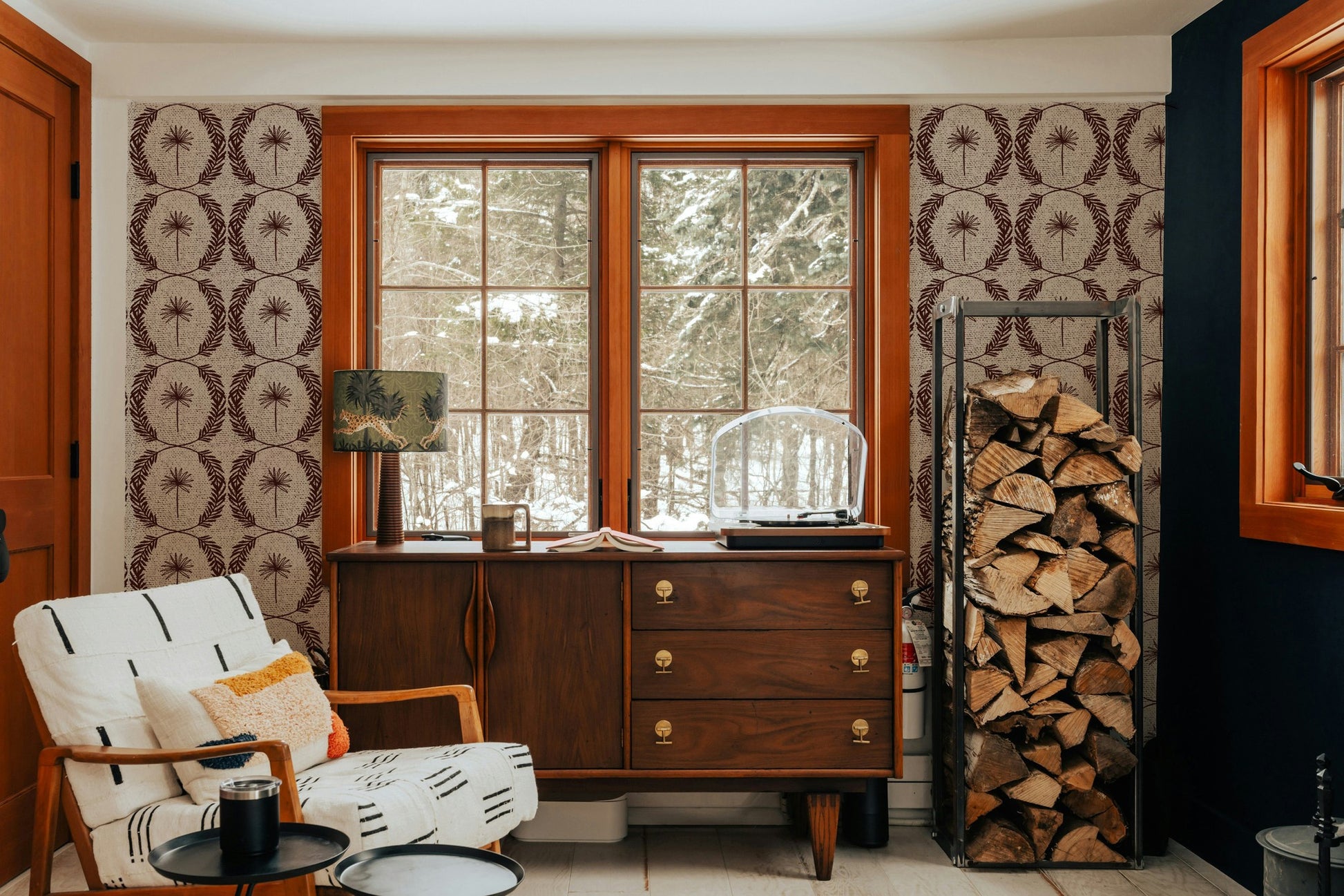 Palm wreath red wallpaper in cozy room with wood accents and mid-century furniture.