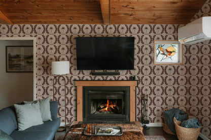Living room with Palm Wreath Red wallpaper, fireplace, and cozy decor.