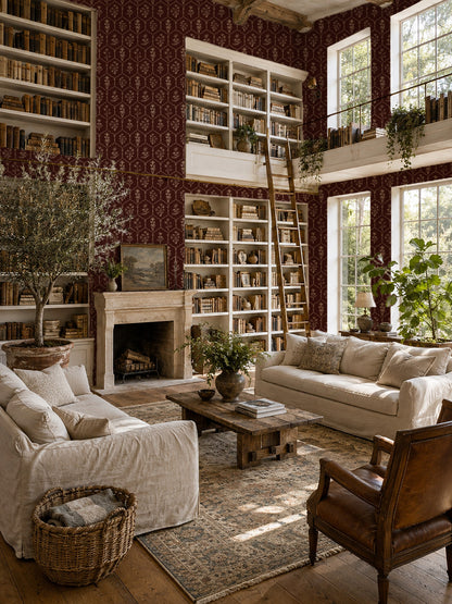 Elegant red floral trellis wallpaper in cozy library with sofas and fireplace.