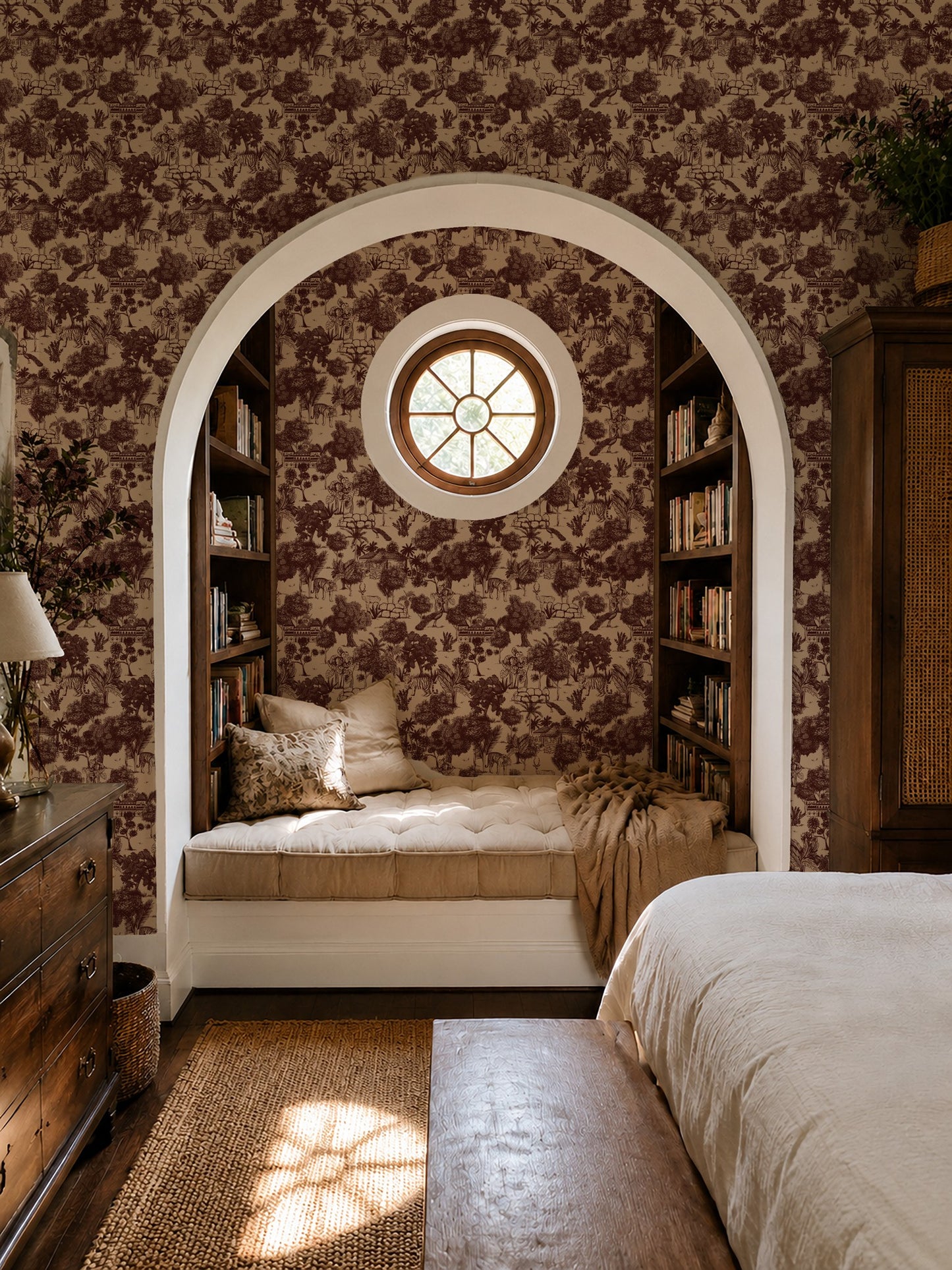Red jungle toile wallpaper in cozy bedroom with archway and bookshelves.