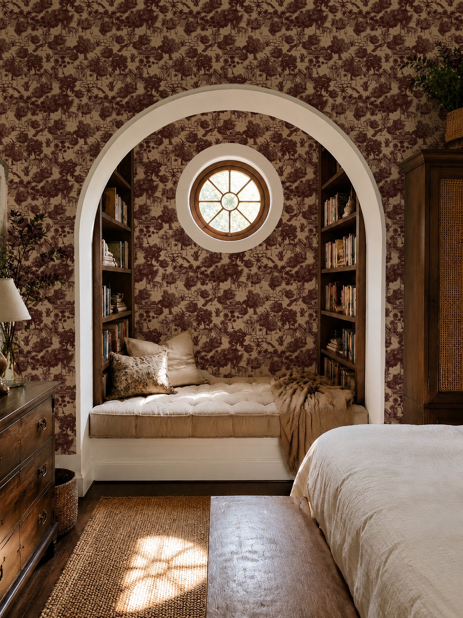 Red jungle toile wallpaper in cozy bedroom with archway and bookshelves.