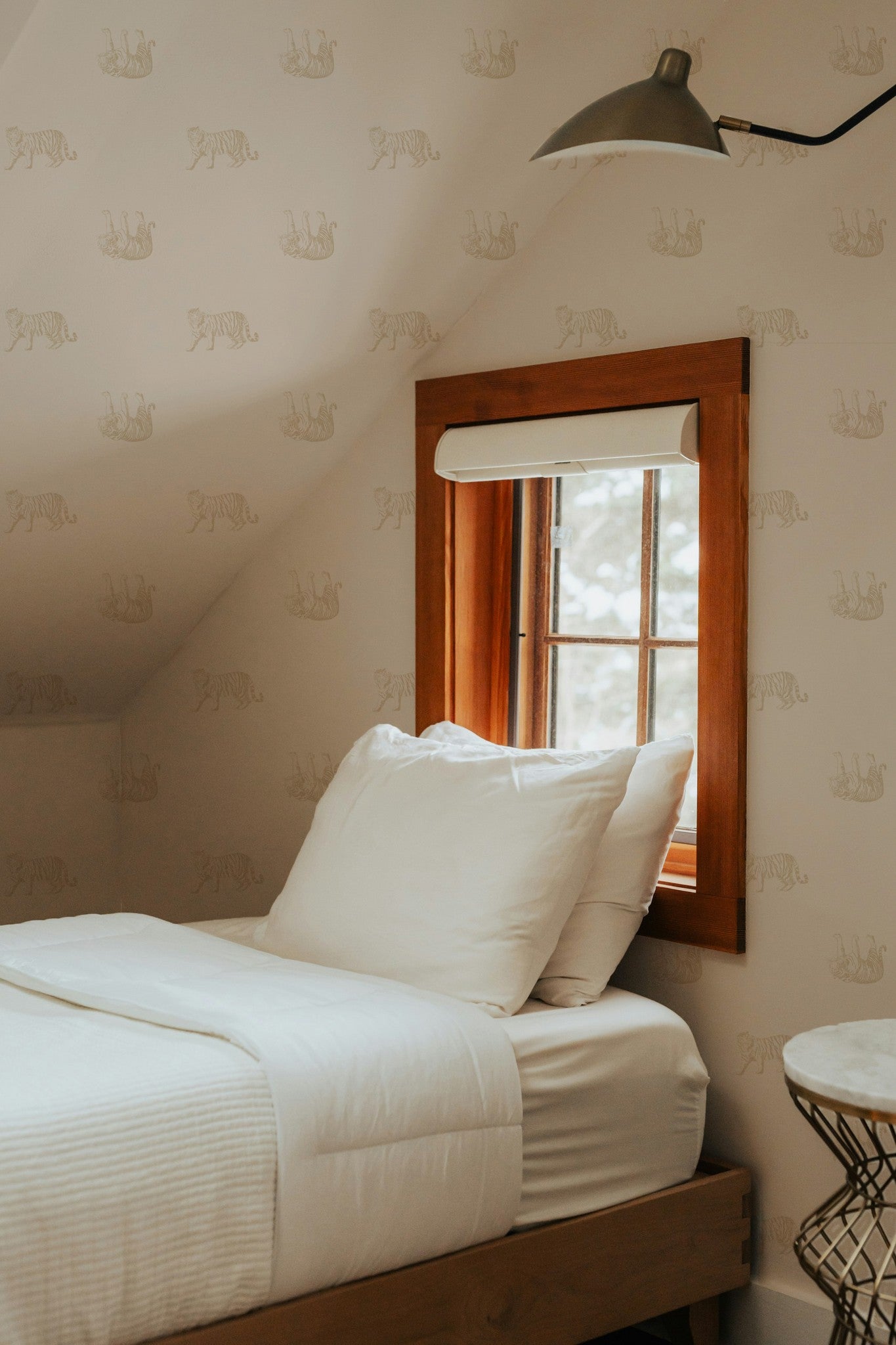 Tiger cream wallpaper in cozy bedroom with wooden window frame and white bedding.