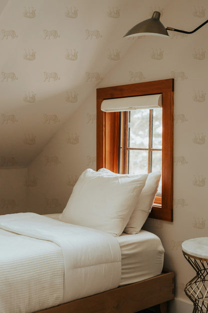Tiger cream wallpaper in cozy bedroom with wooden window frame and white bedding.