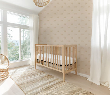 Tiger cream wallpaper in a bright nursery with a wooden crib and wicker chair.