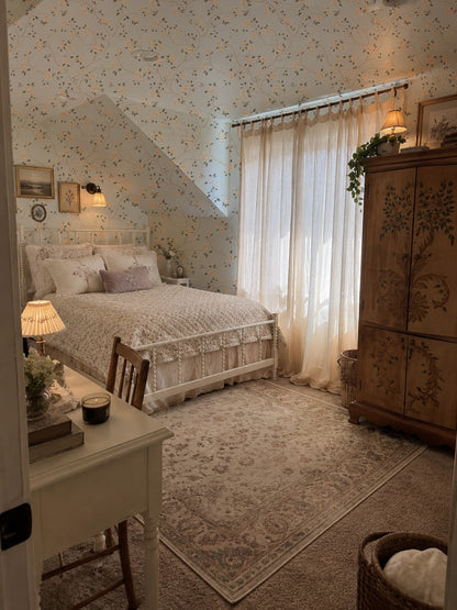 Vintage floral wallpaper with cream roses and hummingbirds in cozy bedroom setting.